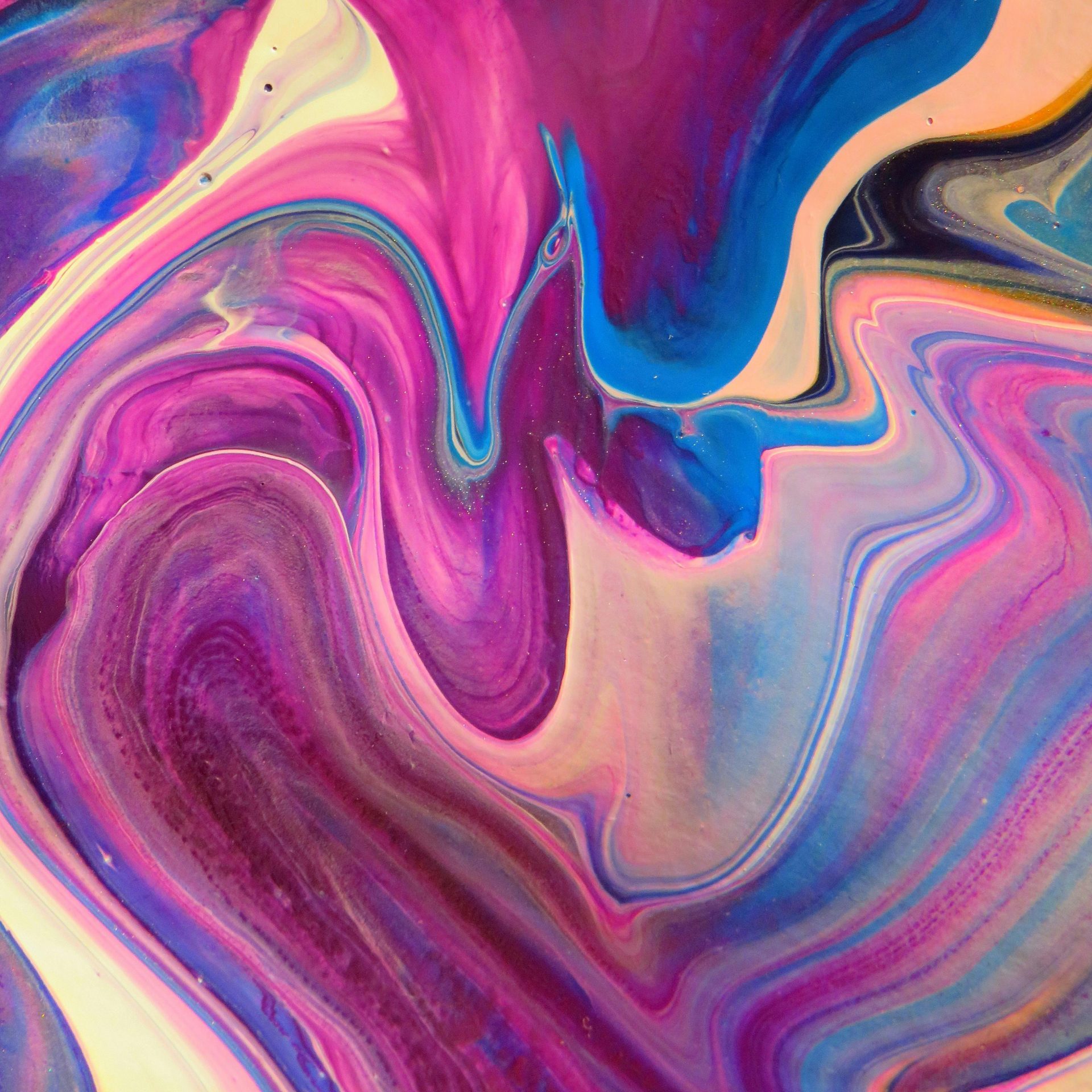 A dynamic abstract artwork featuring swirling patterns in vivid pink, blue, and purple hues.