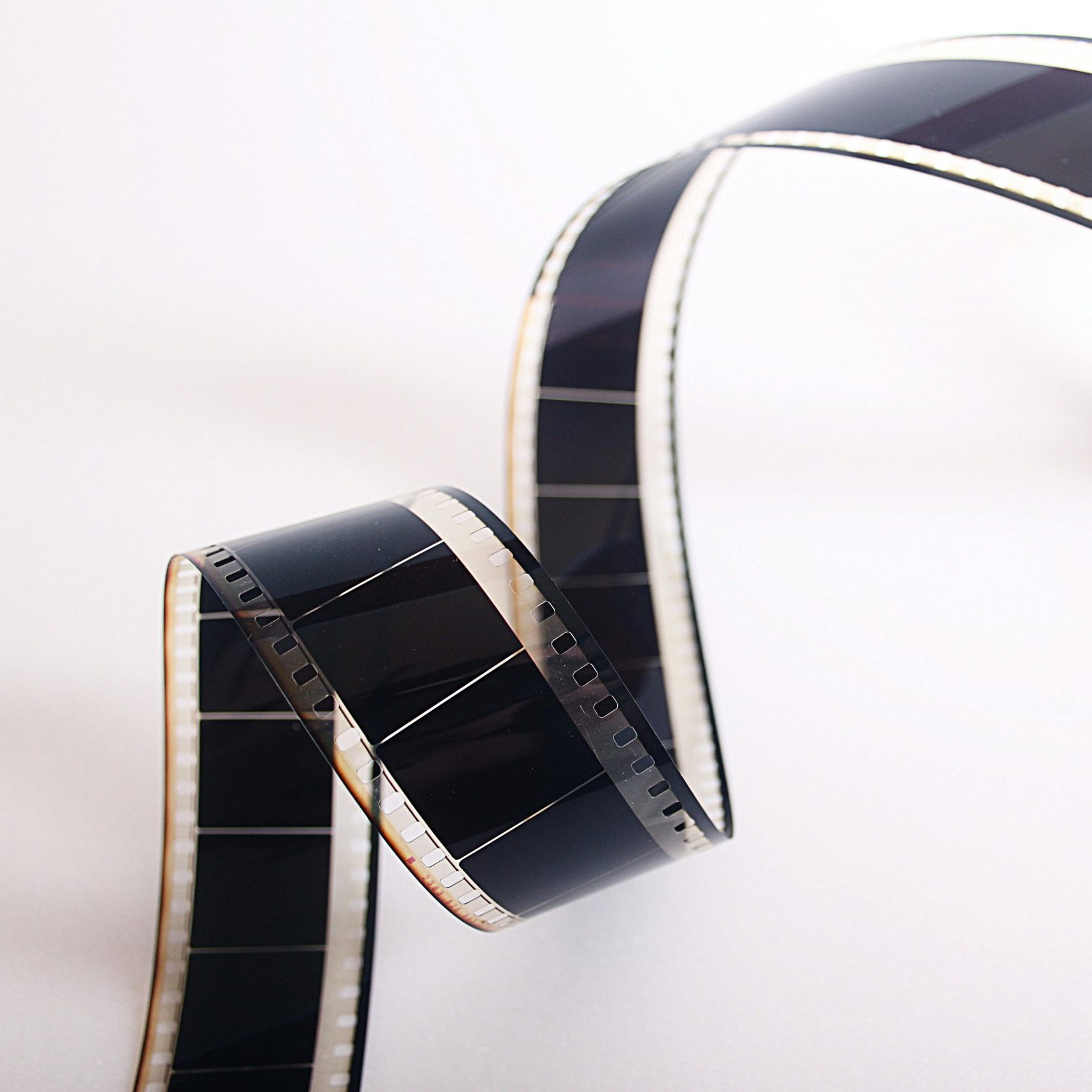 Close-up of a curled filmstrip against a white background, emphasizing vintage cinema.