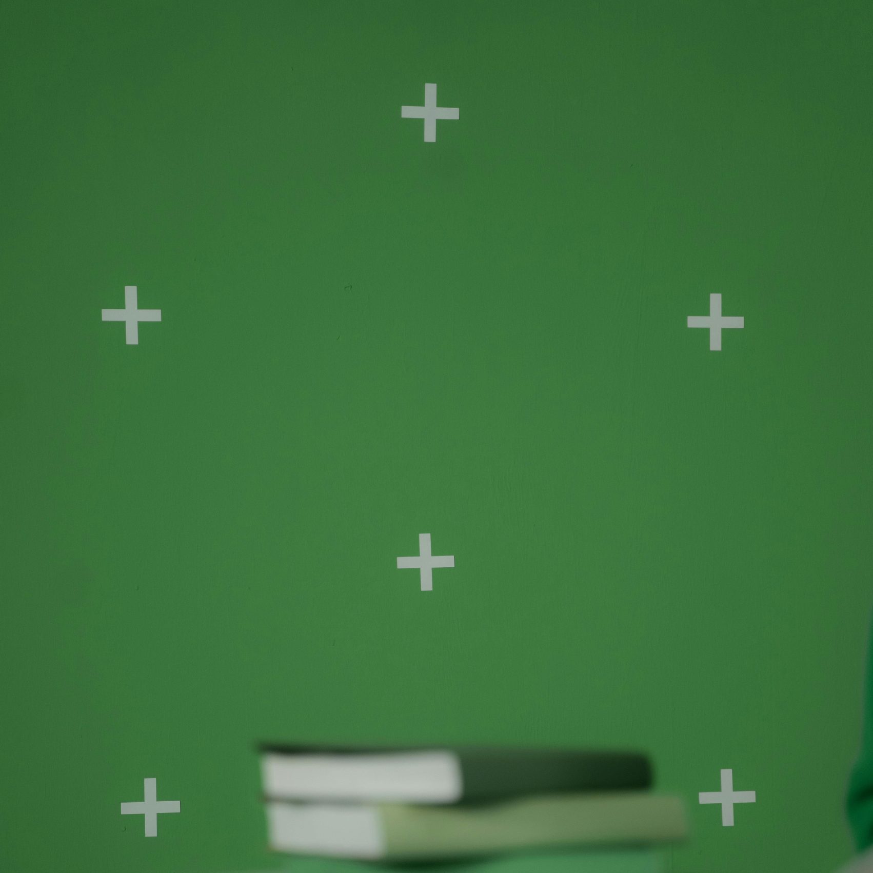 Books placed on a round table against a green chroma key background, ideal for digital media projects.